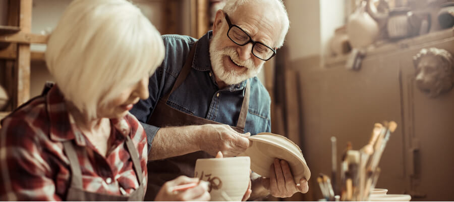 An older couple painting pottery together