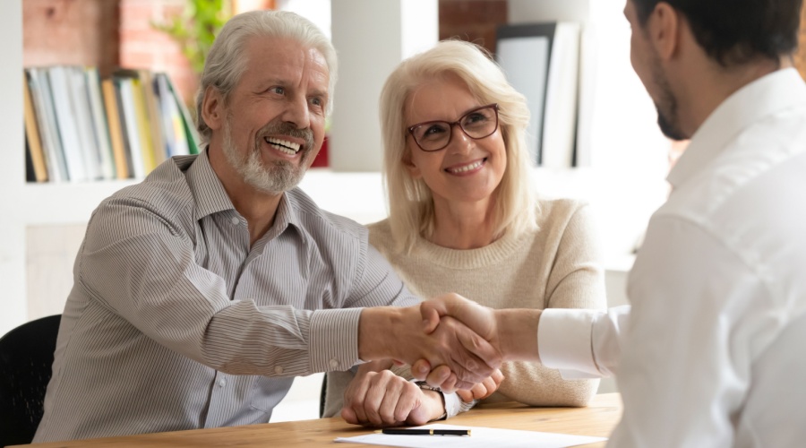 Elder couple shaking hands with advisor