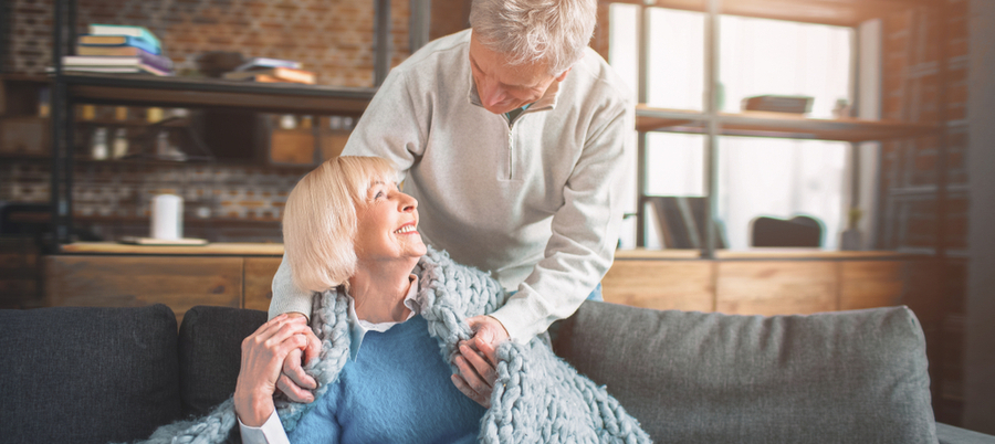 A husband putting on a warm blanket around his wife's shoulders