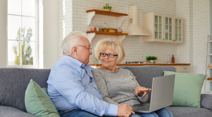 Older couple smiling and looking at laptop