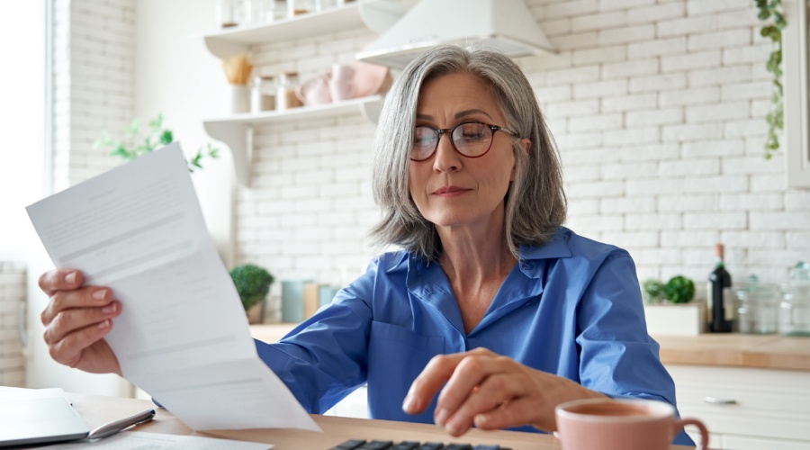 Older lady looking at paper and calculator