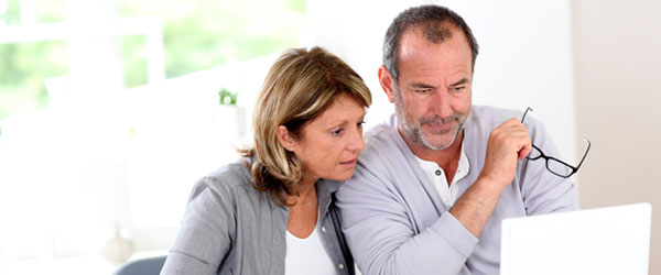 Canadian senior couple browsing the internet on a laptop at home to clarify reverse mortgage myths before making an investment